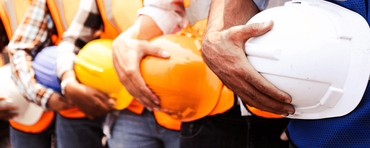 A group of engineer holding thier hard hats at a construction site